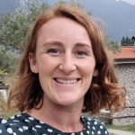 Hanna Duker, CommunityShare team member, smiling in front of outdoor landscape.